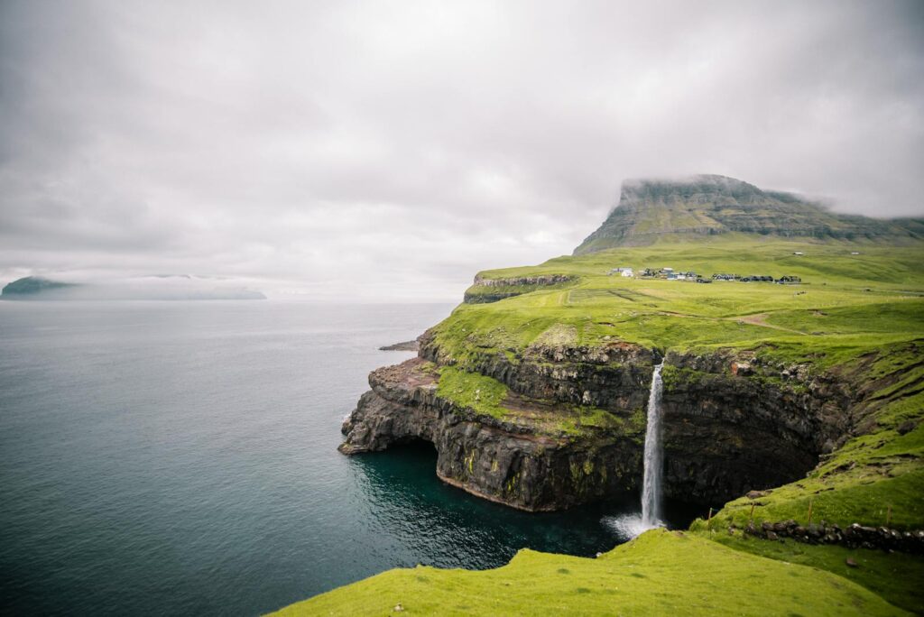 Breathtaking view of the waterfall in Gásadalur, surrounded by lush green cliffs in the Faroe Islands.